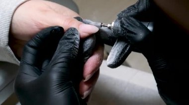 Manikür salonundaki kadının, metal tırnak törpüsüyle güzellik uzmanı tarafından manikür yapıldığı yakın çekim. Spa merkezinde manikür yaptıran bir kadın. Güzellik uzmanı lüks salondaki bir müşteriye çivi çakıyor. Yüksek kalite