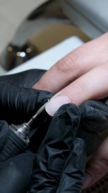 Manikür salonundaki kadının, metal tırnak törpüsüyle güzellik uzmanı tarafından manikür yapıldığı yakın çekim. Spa merkezinde manikür yaptıran bir kadın. Güzellik uzmanı lüks salondaki bir müşteriye çivi çakıyor. Yüksek kalite