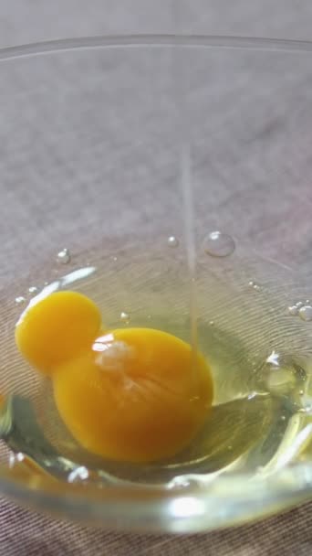 クッキング 生の鶏卵は殴られる前にスパイスで味付けされます 割れた卵が白いセラミックボウルに落ちる 卵を割るためのスローモーションビデオ 高品質の4K映像 — ストック動画
