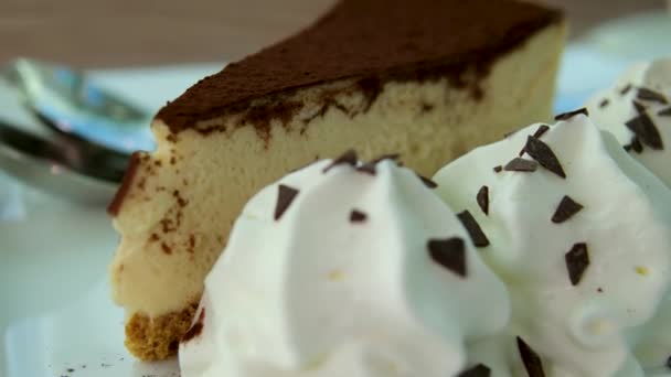 木の背景に古典的なニューヨークスタイルのチーズケーキのスライス ホワイトプレートのおいしいケーキのスライスは デザートフォークで提供されます 高品質の4K映像 — ストック動画