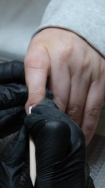 Tırnak manikürünün ayrıntıları dosya ya da fırçayla. Güzel bir tırnak bakımı. Siyah eldivenli manikürcü bej rengi nötr renkte jöle cilasıyla yakın plan güzellik salonu manikürcüsü.
