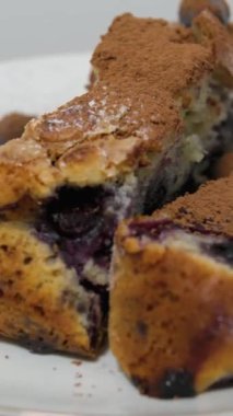 Tahta masadaki beyaz seramik tabakta ev yapımı taze pişmiş yaban mersinli cheesecake dilimini alıyorum. Böğürtlen ve tarçınlı kek.