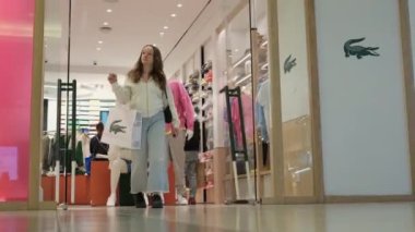 Lacoste mağazasından alışveriş yaparken, bir kız kese kağıdıyla çıkageldi. Bir satıcı kasada ceket satıyor. Güzel giysiler seç. Mağazanın içindeki alışveriş merkezinde. Vancouver Canada 01.01.3024