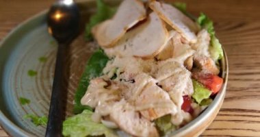 Pakette ahşap çatal bulunan tavuklu Sezar salatası ya da yemek servisi. Beslenme çantasında yemek. 4k video. Yüksek kalite 4k görüntü