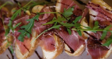 Prosciutto ve incirden sandviç yapma süreci. Kadınların elleri kremalı ekmeğin üzerine bir dilim prosciutto ve incir koyar. Yemek hazırlıklarına yakın çekim. Tabakta bir Apitizer. Yiyecek.. 