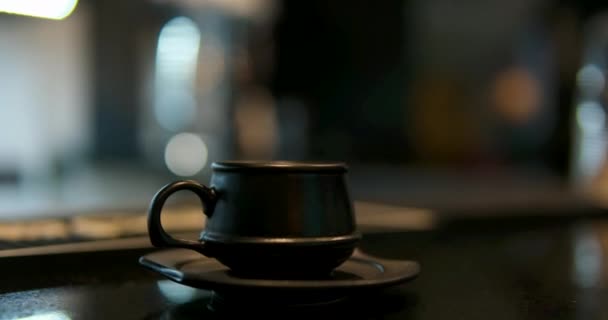 ブラックコーヒーカップ マホガニーテーブルパララックスに黒いマグカップに凍ったカプチーノに埋め込まれたハート 高品質の4K映像 — ストック動画