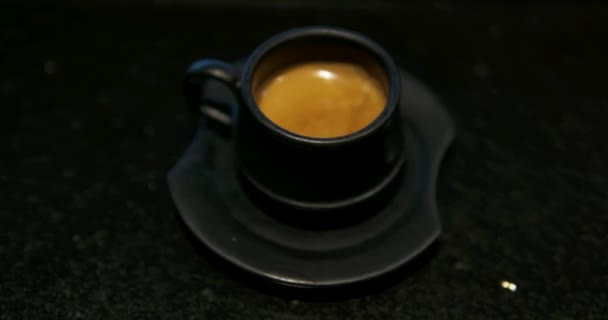 ブラックコーヒーカップ マホガニーテーブルパララックスに黒いマグカップに凍ったカプチーノに埋め込まれたハート 高品質の4K映像 — ストック動画