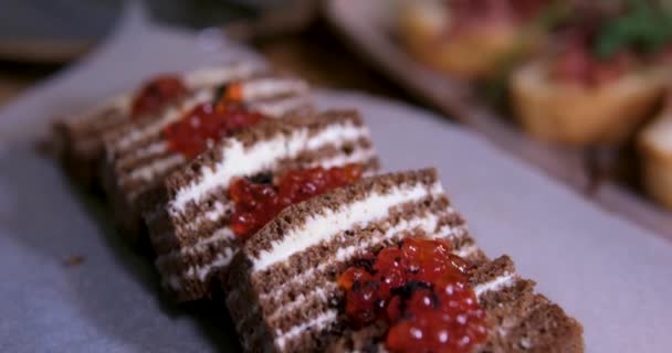 ブラックパンに赤いキャビアとバター レストランのパーチペーパーにケーキの形で黒いパンを塗ったサンドイッチ おいしい 美しい黒と赤のキャビアを皿の上に提供します 高品質で — ストック動画
