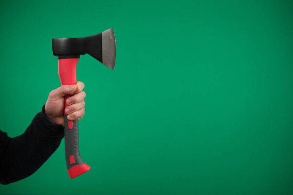Male hand holding an axe with wooden handle. High quality advertising Green background chromakey copy space