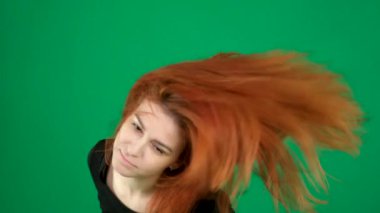 Yeşil arka planda kızıl saçlı dansçı kadını sallıyor, gülüyor, başını çeviriyor, omuzlarıyla dans hareketleri yapıyor, saçlarını düzleştiriyor, mesaj için kromakey alanı yaratıyor. Yüksek kalite