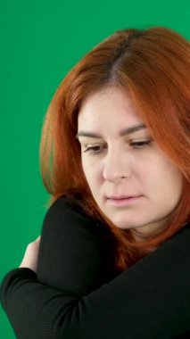 Güç kaybı, üzüntü, kenardan bakmak. Genç yeşil bir kadın başını eğiyor, kaşlarını çatmış, kaşlarını çatmış, saçlarını düzleştirmiş, sitem ediyor. tatsız duygular