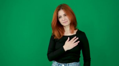 Yeşil arka planda bir kadın elini kalbine koyup söz vermek için başını eğiyor. Tüm saygımla, elinizi yeşil bir krom anahtarın üzerine koyun ve saygının sembolünü koyun. Yüksek kalite