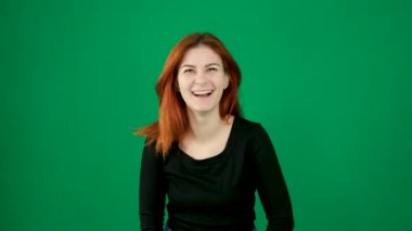 Samimi bir kahkaha, bir kadın gülüyor, gülümsüyor, kollarını yana açıyor, başını kaldırıyor, mutluluk, neşe yeşil bir arka planda, güzel insanlar, kızıl saçlar, inanılmaz bir mutluluk. Yüksek kalite