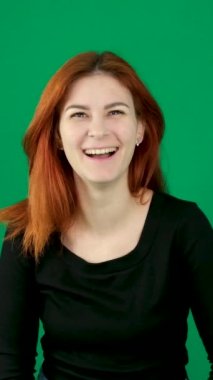 Samimi bir kahkaha, bir kadın gülüyor, gülümsüyor, kollarını yana açıyor, başını kaldırıyor, mutluluk, neşe yeşil bir arka planda, güzel insanlar, kızıl saçlar, inanılmaz bir mutluluk. Yüksek kalite