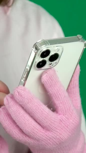 带着粉色冬季手套 带着手机 绿色背景 女人在网上写短信 因特网无线社交网络传播新技术小玩意 高质量的 — 图库视频影像