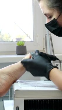 Genç bir kadın güzellik salonundaki kesiciyle pedikür yaptırıyor. Yüksek kalite 4k görüntü