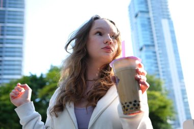 Güzel kız bir kafede pipetten meyve suyu içiyor. köpüklü çay iç. Selfie çek.