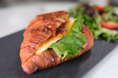 4K Kahvaltı Sahnesi. Bir kadın kahvaltıda pastırmalı kruvasan ve çırpılmış yumurta yiyor. Yüksek kalite 4k görüntü