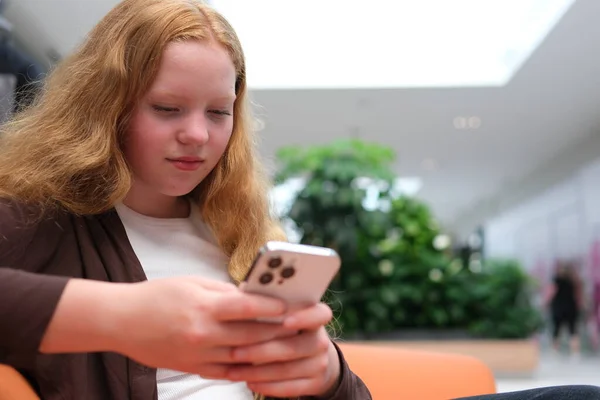 Alışveriş merkezinde oturan bir kız, internet üzerinden arkadaşlarıyla iletişim kurmak için internetten internetten internetten internetten sosyal ağlar yakalıyor, internet oyunları yazıyor, mesajlar yazıyor. Yüksek kalite