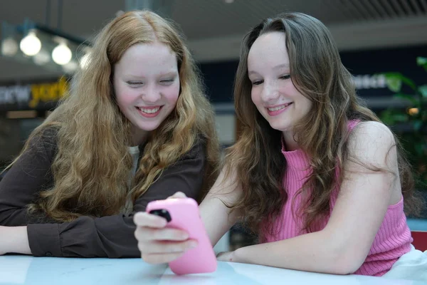 Akıllı telefonlara bakan, mobil oyunlar oynayan, sosyal medyada sohbet eden iki genç kız. Yüksek kalite 