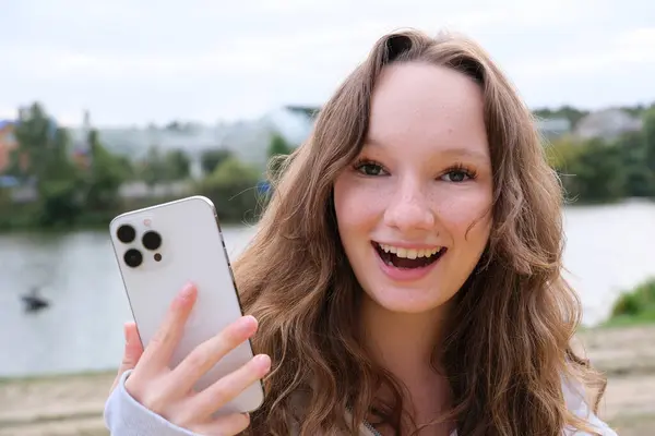 Mutlu genç bir kadın, fotoğraf çektirirken cep telefonu kamerası kullanıyor. Yüksek kalite fotoğraf