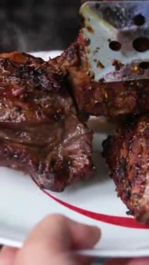 Kömür ızgarasına yakın planda yapılmış büyük, hazır altın kabuklu biftek. Duman ve sıcaklık ızgarada domuz eti pişirir. Dolly sürgülü video. Yüksek kaliteli FullHD görüntüler