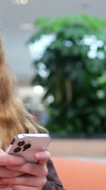 Alışveriş merkezinde oturan bir kız, internet üzerinden arkadaşlarıyla iletişim kurmak için internetten internetten internetten internetten sosyal ağlar yakalıyor, internet oyunları yazıyor, mesajlar yazıyor. Yüksek kalite