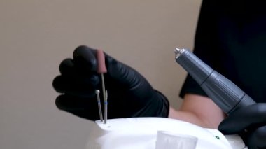 Kuaför salonundaki pedikür uzmanı, güzellik salonundaki ayak temizleme videosuyla ilgileniyor. Tırnaklarını törpülüyor. Siyah eldiven reklamında masaj yapıyor. Bir kadın videosunun hayatı.