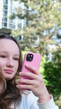 Gökdelenin arka planındaki kız lezzetli bir içecek olan köpüklü çay ve yanmış şekerle selfie çekip sosyal ağlar üzerinden internete yolluyor arkadaşlarıyla saç düzleştiriyor. Yüksek kalite 