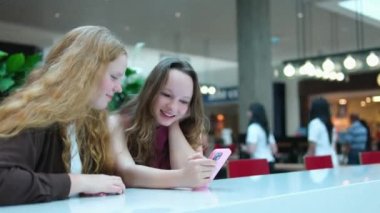 Asyalı kız ve arkadaş etnik Alman-Taylandlı alışveriş merkezinde akıllı telefon özçekimleri yapıyorlar. Yüksek kalite 4k görüntü