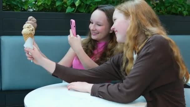 Δύο Νεαρές Γυναίκες Τρώνε Παγωτό Κάθονται Ένα Υπαίθριο Καφέ Διασκεδάζουν — Αρχείο Βίντεο