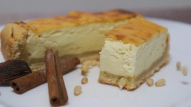 Çam fıstığı serpilmiş tarçın çubukları beyaz tabakta yanmış cheesecake. Yüksek kalite 4k görüntü