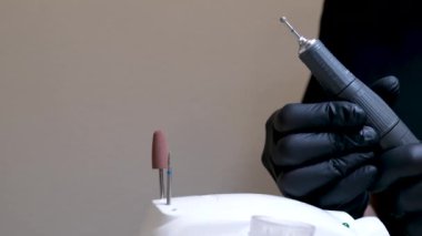Kuaför salonundaki pedikür uzmanı, güzellik salonundaki ayak temizleme videosuyla ilgileniyor. Tırnaklarını törpülüyor. Siyah eldiven reklamında masaj yapıyor. Bir kadın videosunun hayatı.