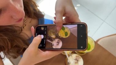 Masada üç farklı içecek. Sağlıklı yiyecek suyu. Ananas suyu. Tuzlu karamel Latte ve buzlu yeşil çay. Spor salonundaki kız kafeteryada cep telefonuyla dinleniyor..