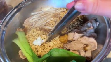 Lokantada geleneksel Vietnam çorbası yapmak, kendi malzemelerinizi seçmek, demir tavaya bir şeyler eklemek, erişte pişirmek, erişteleri kasede döndürerek yemek. Yüksek kalite 4k görüntü