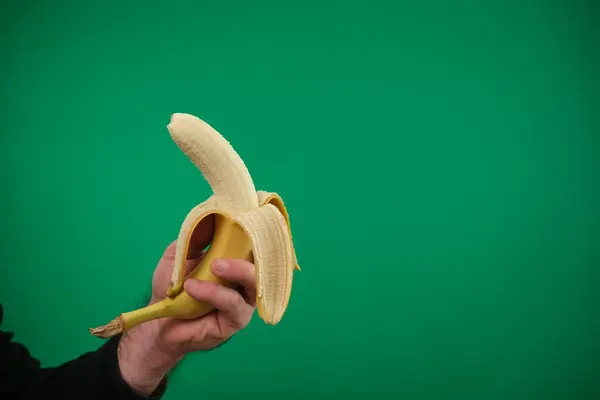 one yellow ripe banana in the man hand . advertising Green background chromakey free space
