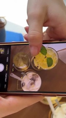 Masada üç farklı içecek. Sağlıklı yiyecek suyu. Ananas suyu. Tuzlu karamel Latte ve buzlu yeşil çay. Spor salonundaki kız kafeteryada cep telefonuyla dinleniyor..