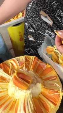 Markette, tüccarlar plastik konteynırdaki yerini satılığa çıkarıp ekmek meyvesi artocarpus altilis 'in kötü bir kısmını kesiyorlar. Yüksek kalite 4k görüntü