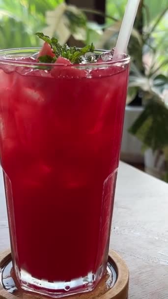 夏天咖啡店里杯子里的鸡尾酒近在咫尺 多汁的西瓜被紫色的稻草西瓜汁刺穿 室内空气中充满了鲜红的饮料 桌上放着冰和石灰 高质量的 — 图库视频影像