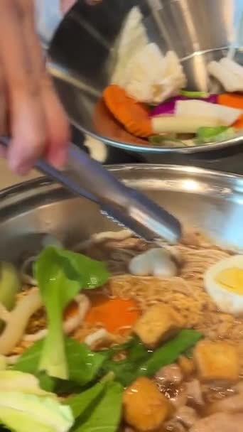 レストランで伝統的なベトナムスープを作り 独自の食材を選択し 鉄鍋に追加し ボウルでラーメンを回す麺で調理します 高品質の4K映像 — ストック動画
