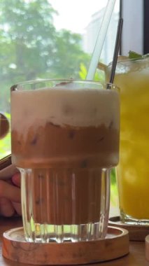 Masada üç farklı içecek. Sağlıklı yiyecek suyu. Ananas suyu. Tuzlu karamel Latte ve buzlu yeşil çay. Spor salonundaki kız kafeteryada cep telefonuyla dinleniyor..