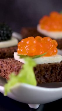 Masa arkasında siyah ve kırmızı havyar olan bölünmüş bir tabak. Yüksek kalite fotoğraf