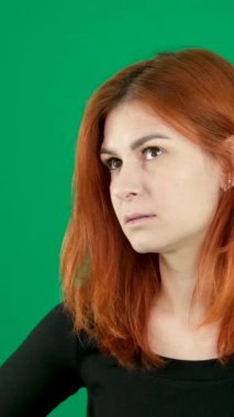 Kızıl saçlı, yeşil arka planda genç bir kadın. Krom anahtarlı. Umutsuzluk, gözlerde keder. psikolojik kriz