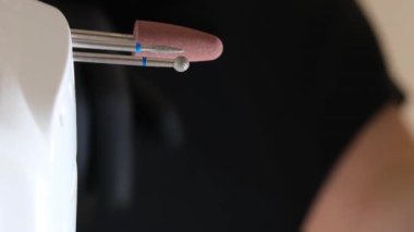 Manikür ve pedikür yapan kadın pedikür yapmadan önce manikür makinesiyle müşterilerinin tırnaklarındaki jöle kabuk cilasını temizler. Güzellik uzmanı eski verniği manikür makinesiyle çıkarıyor. Jölenin çıkarılması. 