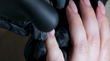 Manikür ve pedikür yapan kadın pedikür yapmadan önce manikür makinesiyle müşterilerinin tırnaklarındaki jöle kabuk cilasını temizler. Güzellik uzmanı eski verniği manikür makinesiyle çıkarıyor. Jölenin çıkarılması. 