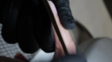 Manikür ve pedikür yapan kadın pedikür yapmadan önce manikür makinesiyle müşterilerinin tırnaklarındaki jöle kabuk cilasını temizler. Güzellik uzmanı eski verniği manikür makinesiyle çıkarıyor. Jölenin çıkarılması. 