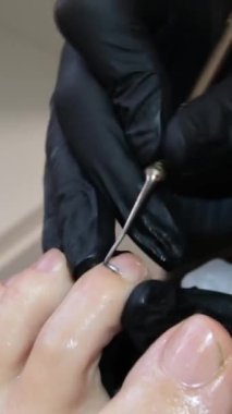 Manikür ve pedikür yapan kadın pedikür yapmadan önce manikür makinesiyle müşterilerinin tırnaklarındaki jöle kabuk cilasını temizler. Güzellik uzmanı eski verniği manikür makinesiyle çıkarıyor. Jölenin çıkarılması. 