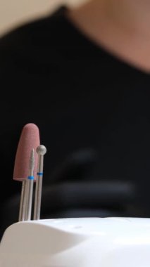 Manikür ve pedikür yapan kadın pedikür yapmadan önce manikür makinesiyle müşterilerinin tırnaklarındaki jöle kabuk cilasını temizler. Güzellik uzmanı eski verniği manikür makinesiyle çıkarıyor. Jölenin çıkarılması. 