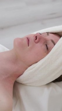 Güzellik, kaplıca ve kadın dinlenmek için güzellik salonunda yüz masajı yaptırıyor. Cilt bakımı için sakin, huzurlu ve lüks bir tedavi stresi azaltmak için masaj terapisi, cilt bakımı ve müşteriye masaj yapan güzellik uzmanı.