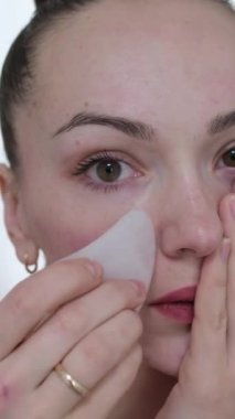 Üstat, beyaz havluyla pembe taşlı kıza yüz masajı yapıyor. Pembe taş kazıyıcı. Yüz rengi. Yavaş çekim videosu. Yüksek kalite